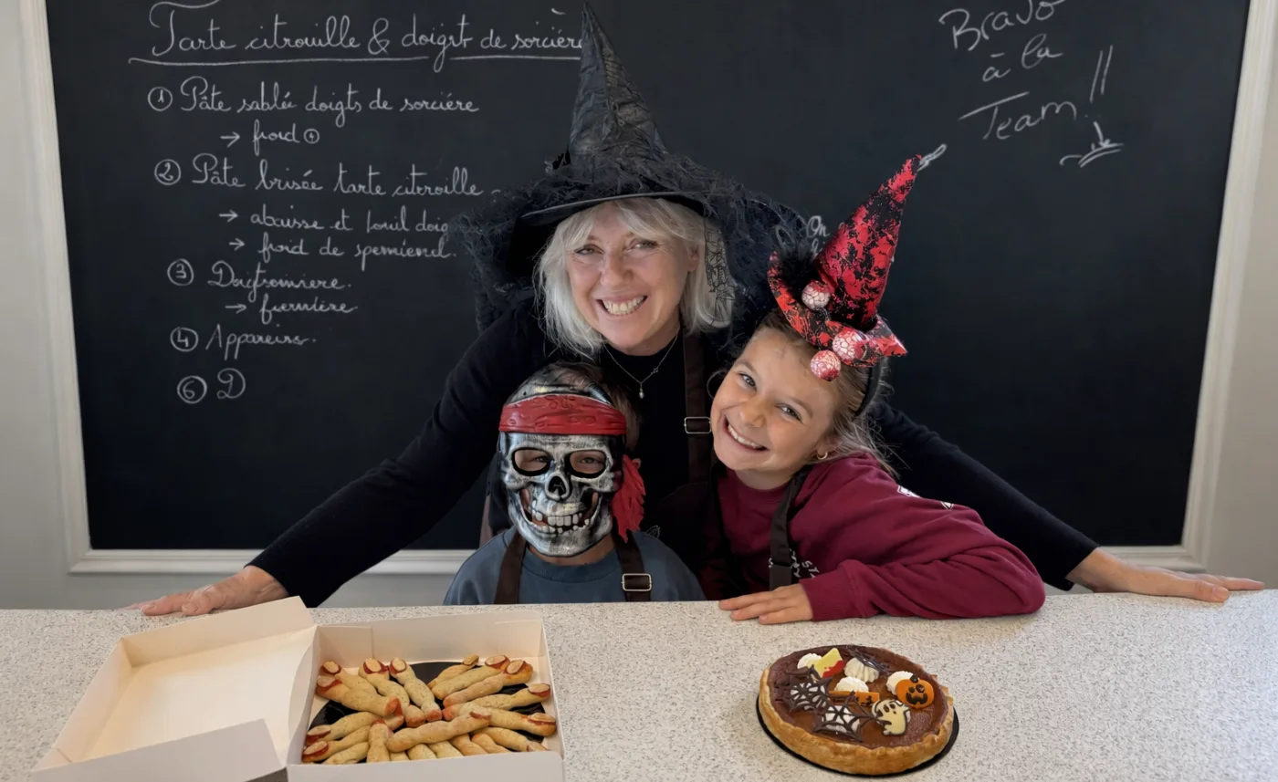 Atelier de pâtisserie d’Halloween : Cécile et deux enfants déguisés présentent une tarte à la citrouille et des doigts de sorcière